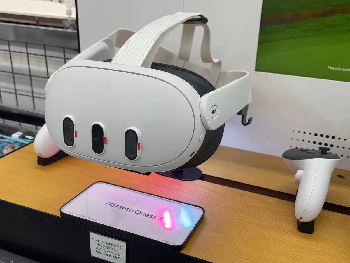A white Meta Quest 3 headset on a shop display, with its two controllers beside it