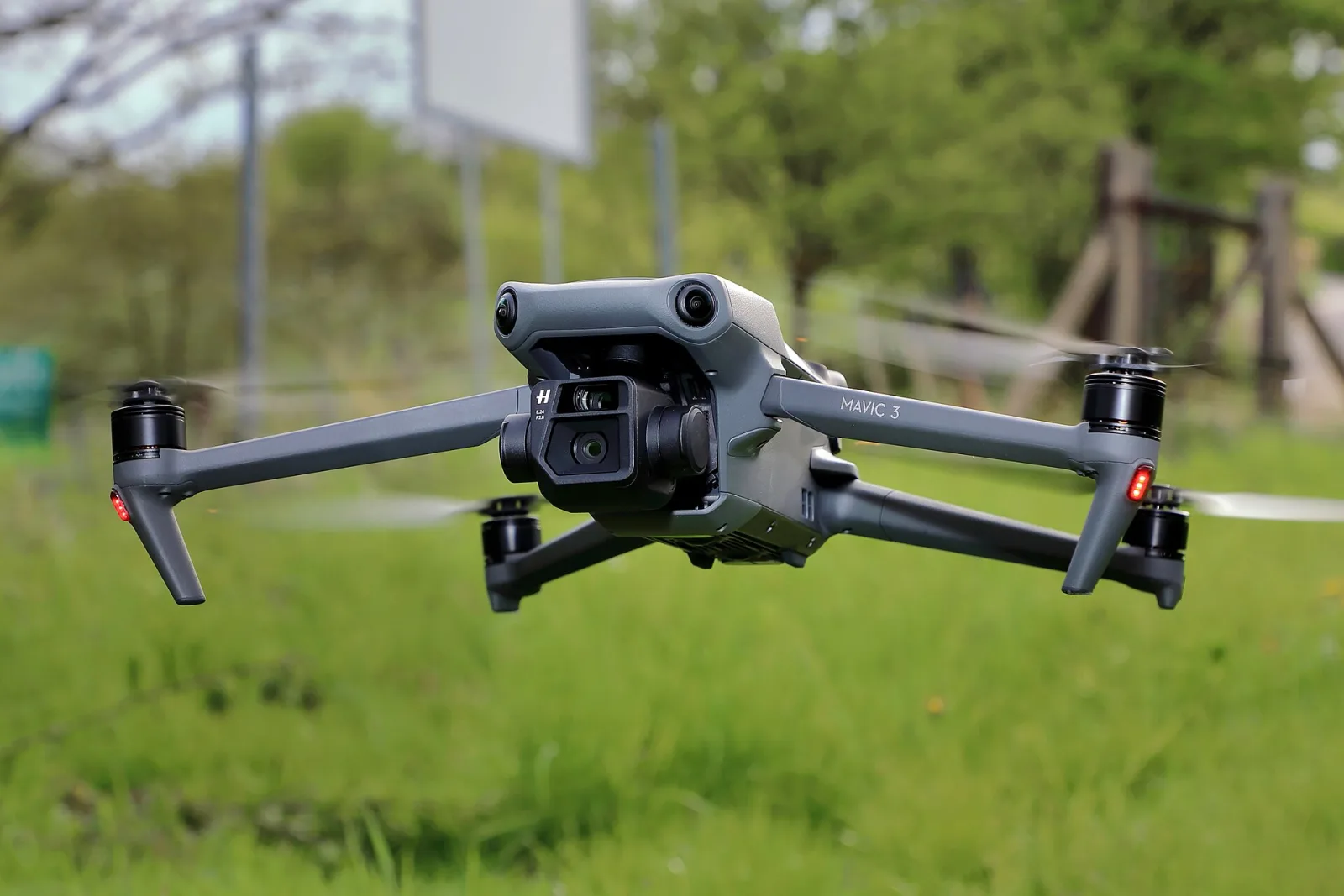 A grey DJI Mavic 3 drone in flight, close up, above a grassy field